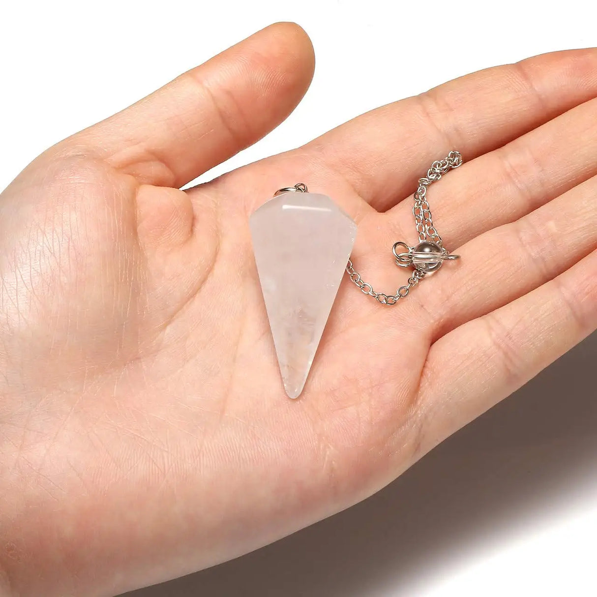 Hand holding a rose quartz crystal pendant on a white background