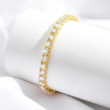 Gold bracelet with clear stones on a white surface