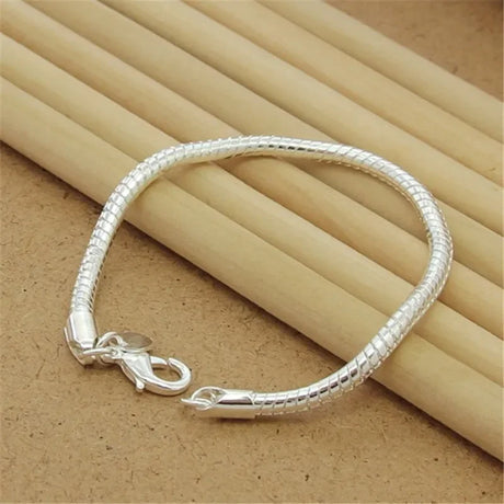 Silver bracelet on a textured surface with wooden sticks