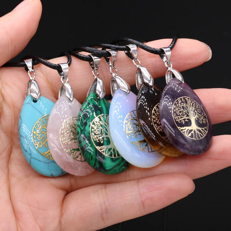 Set of colorful stone pendants with tree-of-life design on a hand against a black background