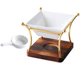 White ceramic bowl with gold rim on a wooden stand with a small white scoop, on a white background