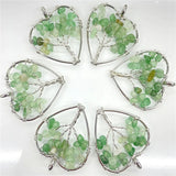 Five green gemstone pendants in silver wireframe designs on a white background