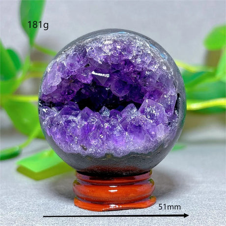 Amethyst geode crystal sphere with a red base on a light background