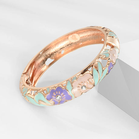 Rose gold ring with floral designs and gemstones on a light gray background