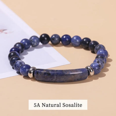Blue beaded bracelet with a silver bar on a beige background, labeled '5A Natural Sosalite'.