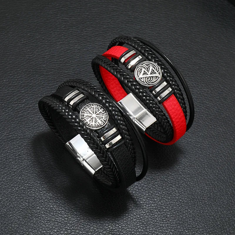 Two black leather bracelets with red accents and silver metal clasp on a dark textured surface