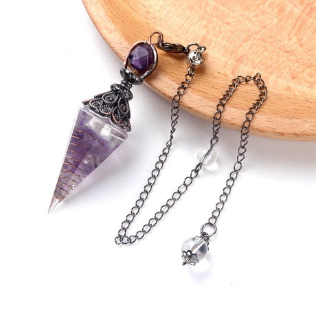 Crystal pendulum with chain on a wooden surface