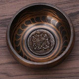 Decorative bronze bowl with intricate patterns on a wooden surface
