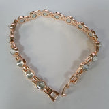 Rose gold bracelet with clear gemstones on a light gray background