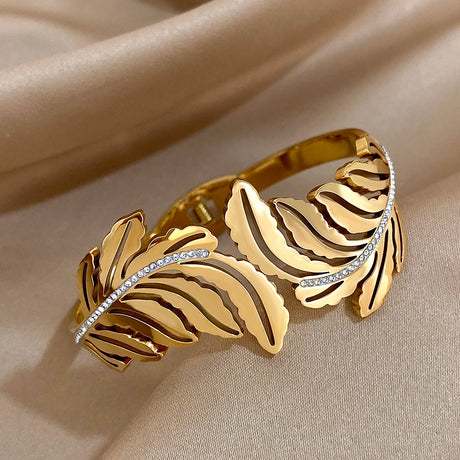 Gold bracelet with leaf-like design on a beige fabric background