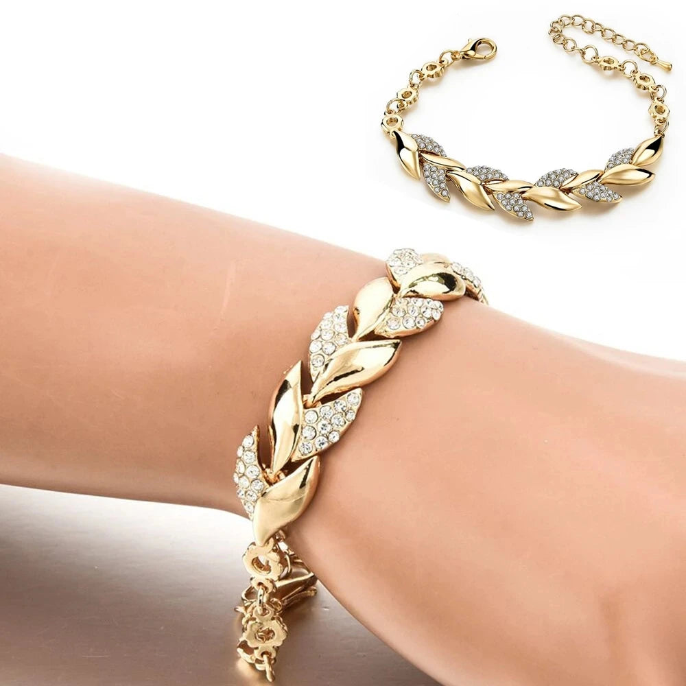 Gold bracelet with leaf design on a wrist against a white background