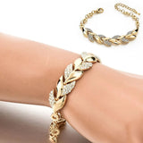 Gold bracelet with leaf design on a wrist against a white background