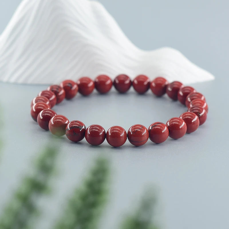 Red beaded bracelet on a white shell with a blurred natural background