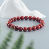 Red beaded bracelet on a white shell with a blurred natural background