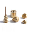 Set of gold-colored metal incense holders on a white background