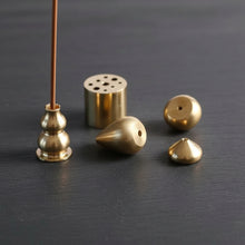 Set of gold-colored metal incense holders on a white background