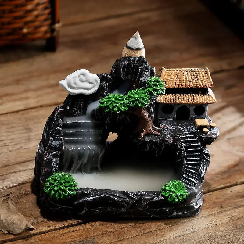 Decorative miniature scene with a house, trees, and water feature on a wooden surface