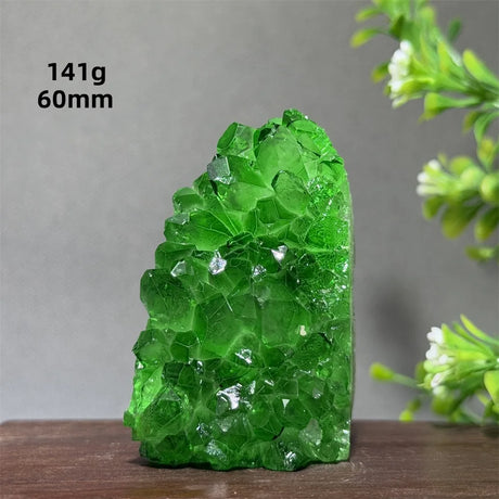 Green crystal rock on a wooden surface with a gray background and plant elements.