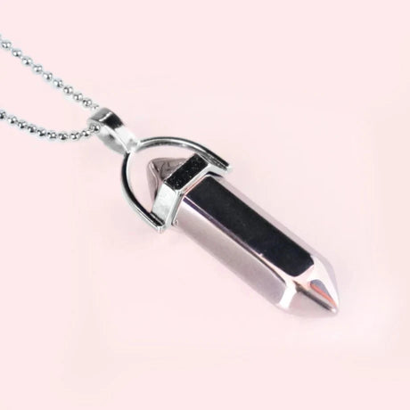 Silver and black pendant necklace on a pink background