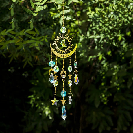 Decorative hanging ornament with celestial design against a green leafy background
