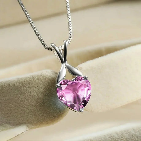 Pink heart-shaped gemstone necklace on a beige background