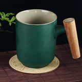 Green mug with wooden handle on a coaster, dark background