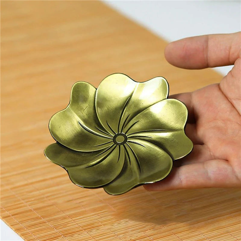 Gold flower-shaped object held by a hand on a wooden surface
