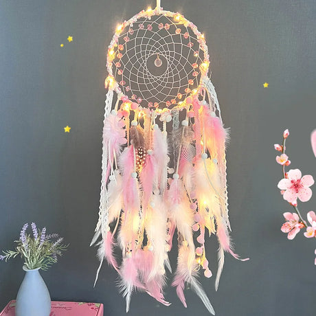Decorative dreamcatcher with feathers and lights against a dark background