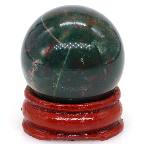Green and red marbled stone sphere on a red stand against a white background