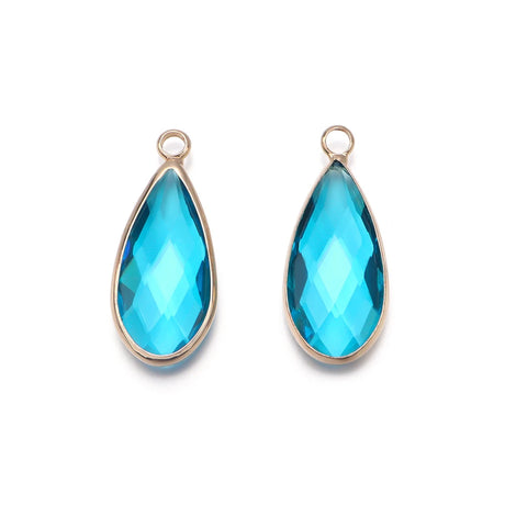 Teardrop-shaped blue gemstones with gold settings on a white background