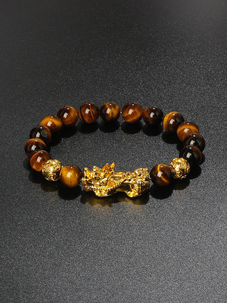 Bracelet with tiger eye beads and gold dragon charm on a dark background