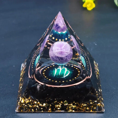 Decorative crystal pyramid with purple sphere and zodiac symbol on a dark background