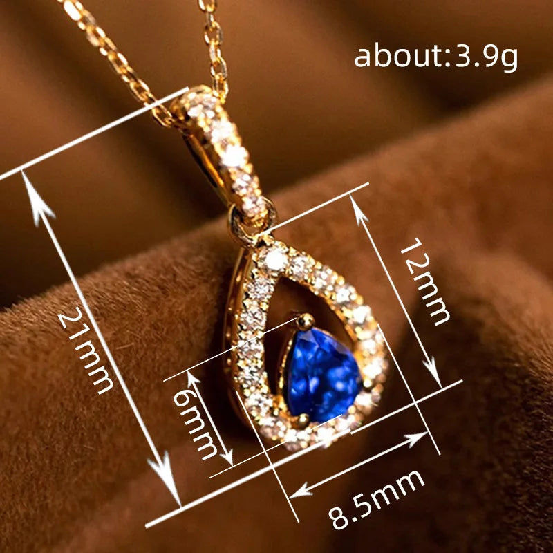 Gold pendant with blue gemstone and measurements on a brown background