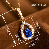 Gold pendant with blue gemstone and measurements on a brown background