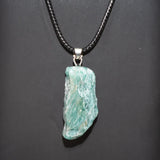 Turquoise stone pendant on a black cord against a dark background