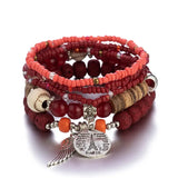 Stack of red beaded bracelets with charms on a white background