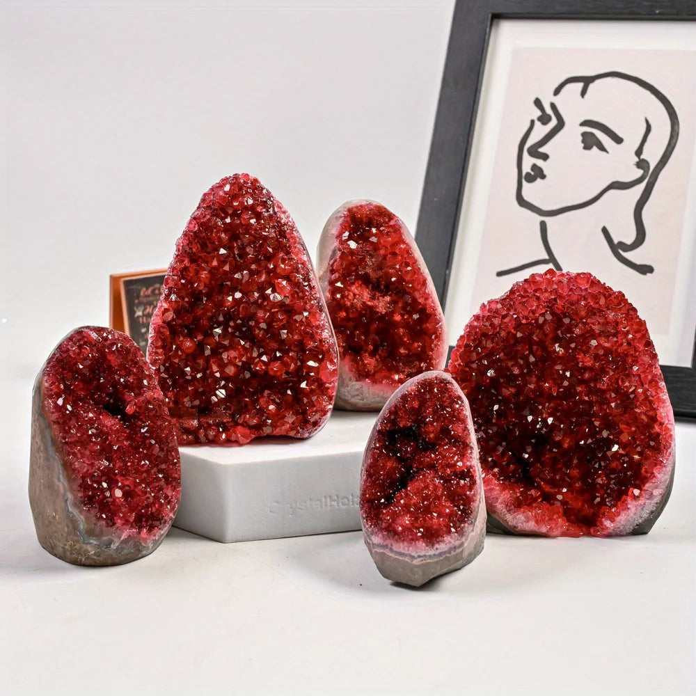 Red glittery geode crystals on a white surface with a framed black and white portrait in the background.