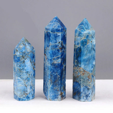 Three blue crystal points on a white surface with a gray background