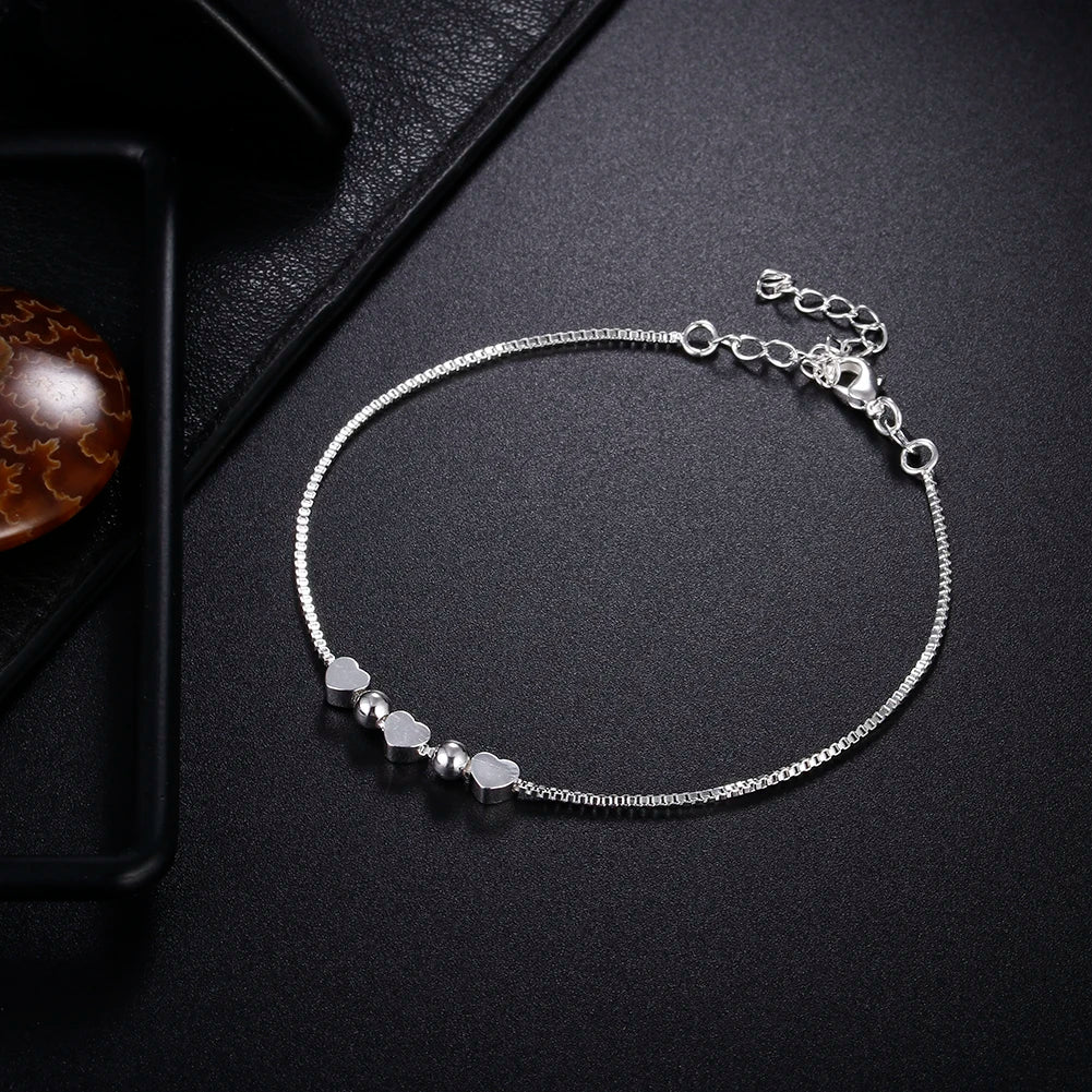 Silver anklet with beads on a dark surface