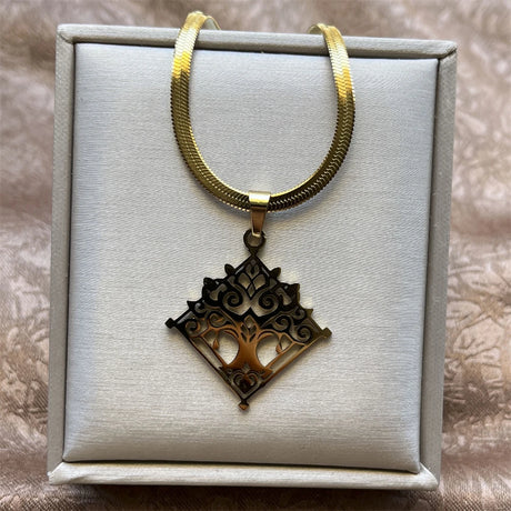 Gold necklace with a detailed pendant on a textured surface