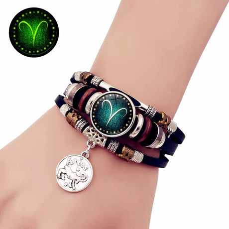 Multistrand bracelet with a zodiac charm on a wrist, glowing in the dark.