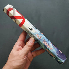 Hand holding a 'Anti Tabaco' product against a dark background