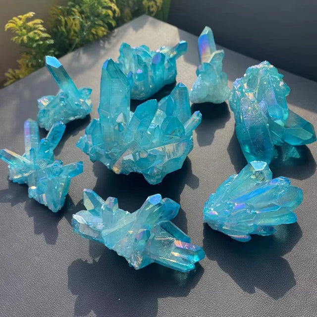 Collection of blue crystal formations on a dark surface with greenery in the background