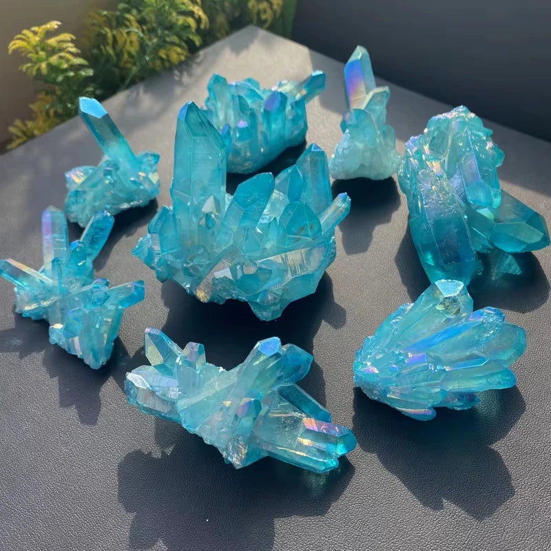 Collection of blue crystal formations on a dark surface with greenery in the background