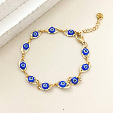 Gold bracelet with blue evil eye charms on a light beige background
