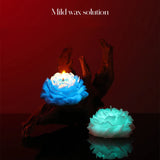 Two glowing flower-shaped candles on a dark surface with a red background