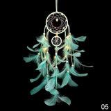 Turquoise feather dreamcatcher with lights on a black background