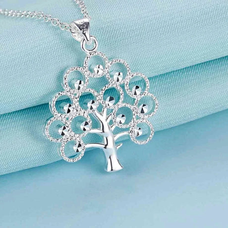 Silver tree-shaped pendant necklace on a light blue satin background