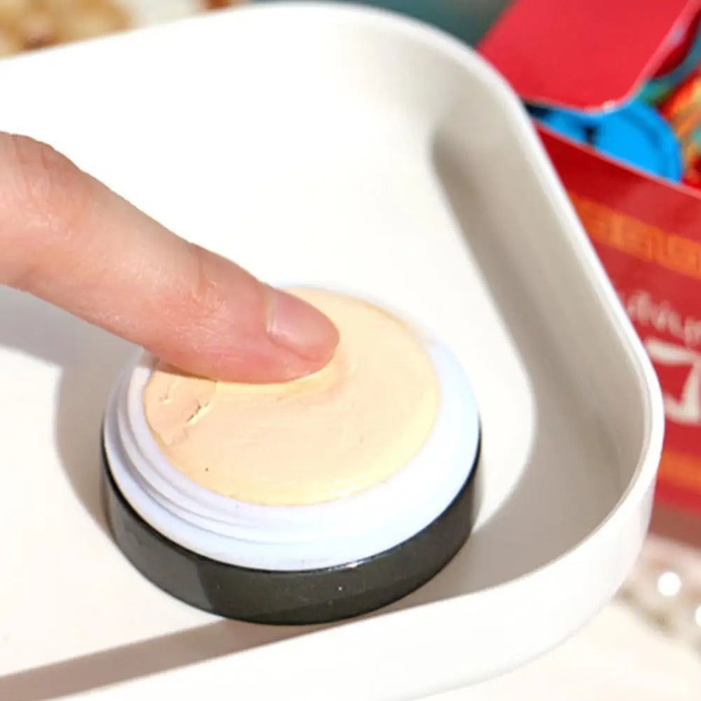 Hand pressing a compact powder into a white dish with a blurred background