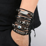 Multiple black and silver bracelets on a wrist against a neutral background